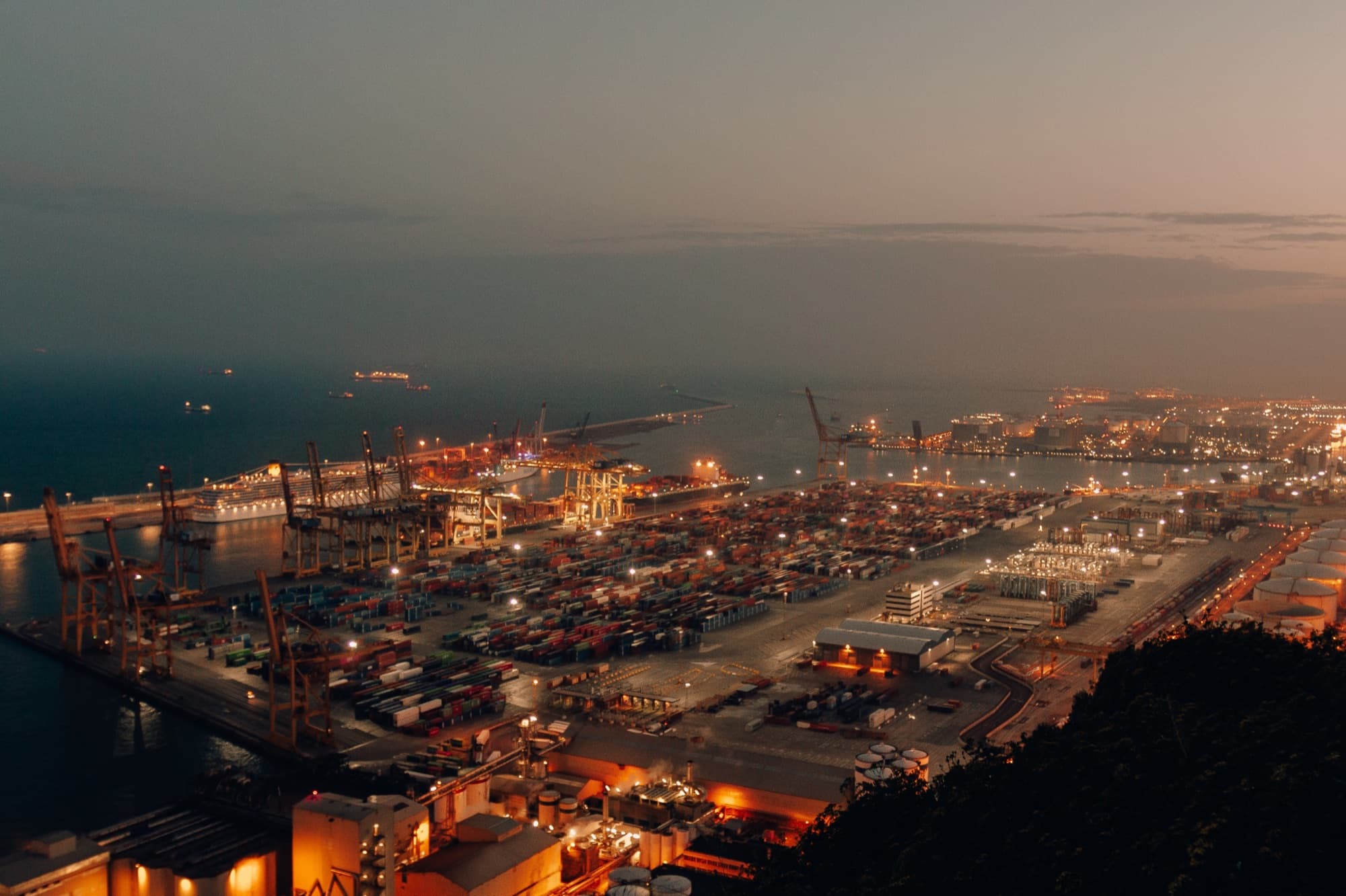 Aerial view of a container port at night with vehicles staged for export
